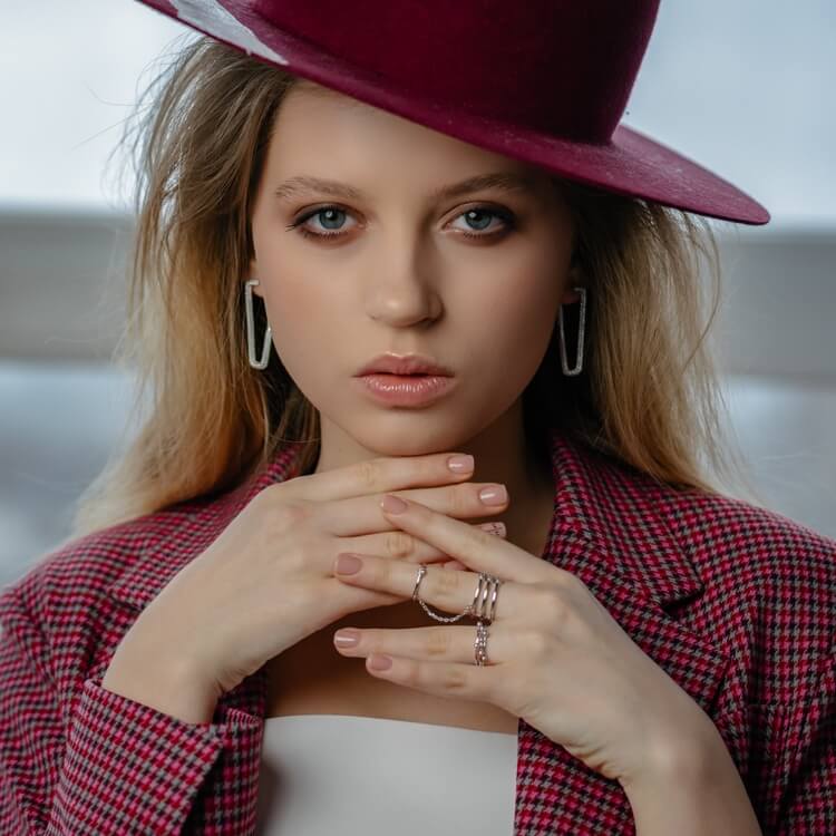 Stylist seated in a softly lit studio wearing a cream knit